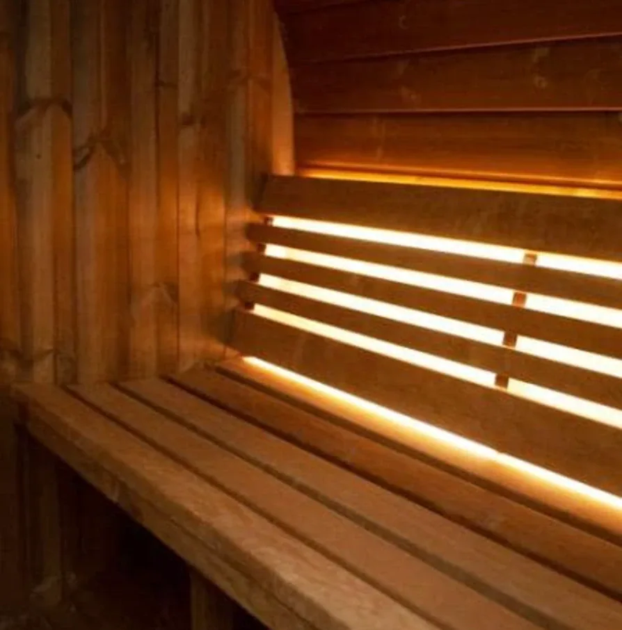 Close-up of a cedar bench and slatted backrest inside the sauna, softly lit